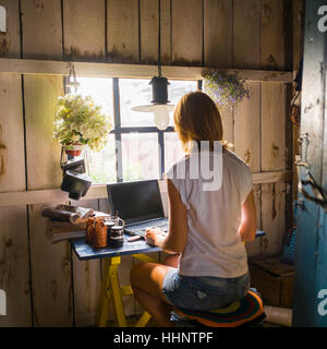 Caucasian woman using laptop near rustic window Stock Photo