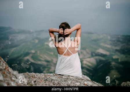Caucasian woman sitting on rock overlooking landscape Stock Photo