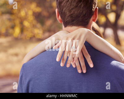 Hands of woman wearing engagement ring hugging man Stock Photo