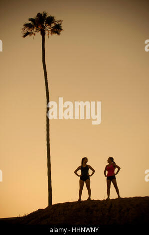 Mixed Race mother and daughter standing near palm tree Stock Photo