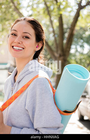 Thai woman posing in city carrying exercise mat Stock Photo