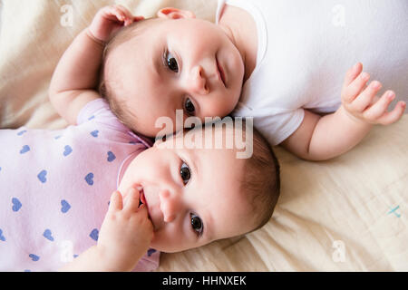 Caucasian twin baby girls laying on bed Stock Photo