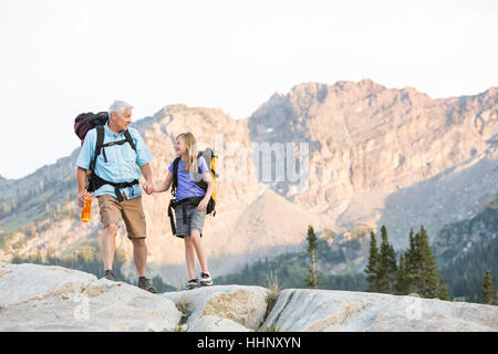 Caucasian grandfather and granddaughter hiking on mountain Stock Photo