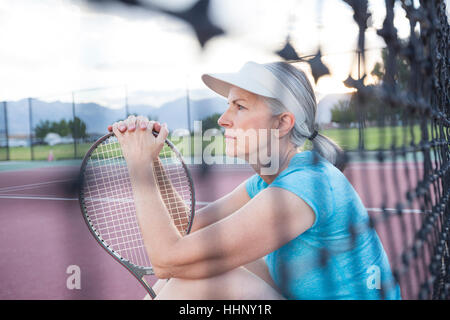 Caucasian woman resting and holding tennis racket Stock Photo