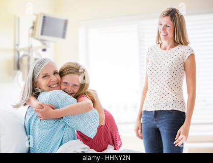 Caucasian granddaughter hugging grandmother in hospital Stock Photo