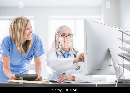 Caucasian doctor and nurse using computer at desk Stock Photo