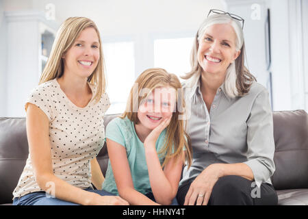 Portrait of women and girl sitting on sofa Stock Photo
