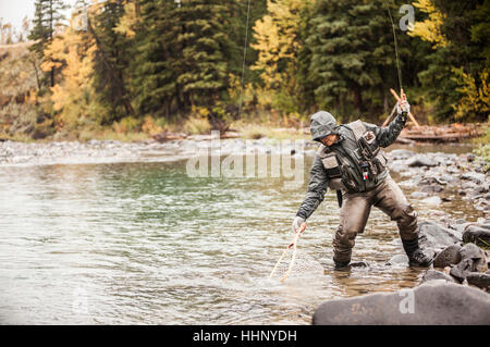 Caucasian man fishing in river holding net Stock Photo