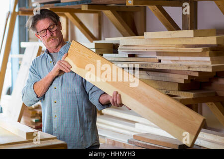 Caucasian carpenter eyeballing wooden plank in workshop Stock Photo