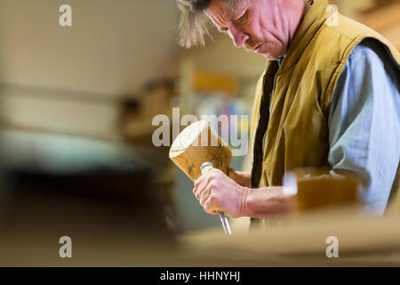 Caucasian carpenter using mallet and chisel in workshop Stock Photo
