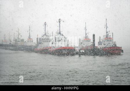 Snow drifting over Elbe river and  tugs at Neumuehlen in the harbor of Hamburg, Germany Stock Photo
