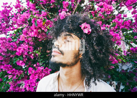 Portrait of Mixed Race man smelling flowers Stock Photo