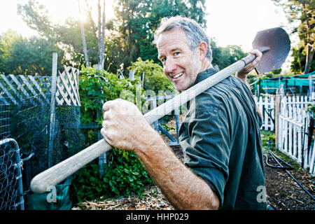 Portrait of Caucasian man carrying shovel in garden Stock Photo