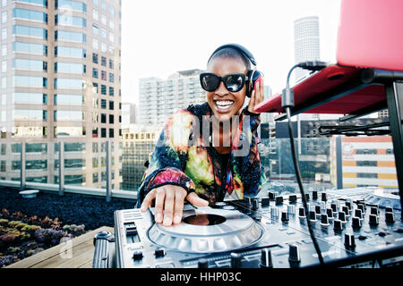 Smiling Black DJ on urban rooftop Stock Photo
