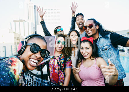 Friends smiling with DJ on urban rooftop Stock Photo