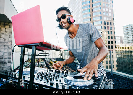 Smiling Black DJ on urban rooftop Stock Photo