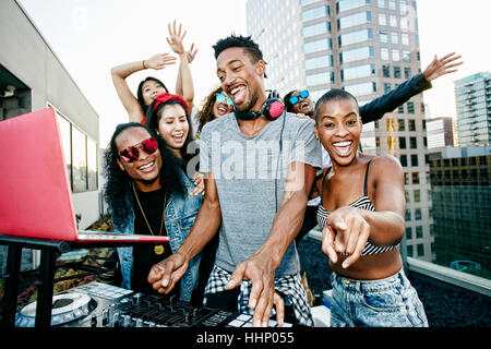 Friends posing with DJ on urban rooftop Stock Photo