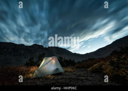 Illuminated camping tent under cloudy sky