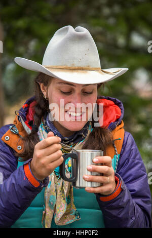 Caucasian woman using spoon with metal cup in winter Stock Photo