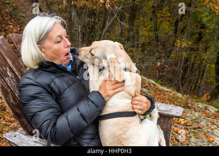 Caucasian woman holding dog in lap outdoors