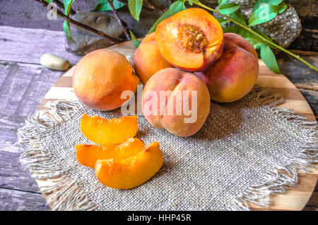 Whole and sliced peaches lying on a cutting board Stock Photo
