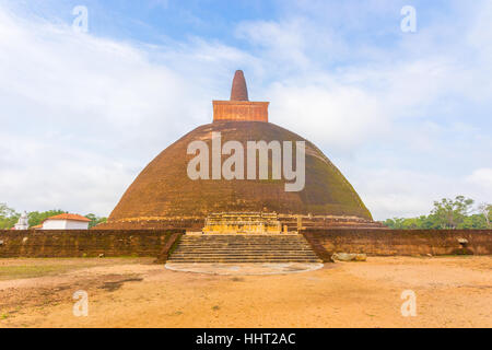 Dirt field foreground leading to steps of Abhayagiri Dagoba ruins on a beautiful blue sky day in ancient capitol of Anuradhapura Stock Photo