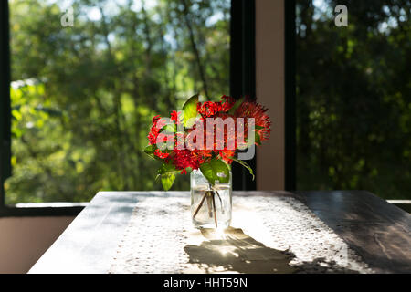 ixora flower in vase on wood table near window with garden view in living room Stock Photo