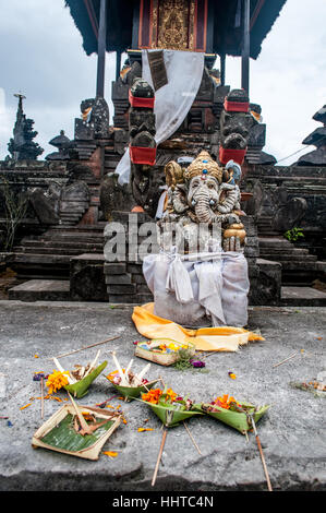 Religious offering in front of a stone statue of Ganesha, Pura Ulun Danu Batur, Bali, Indonesia Stock Photo