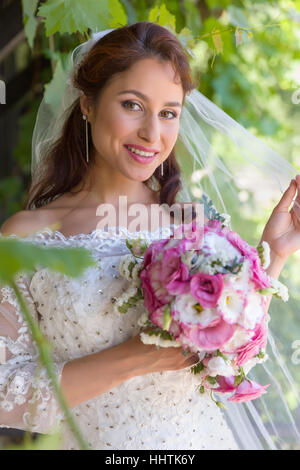 Stunning young bride posing in a green summer garden Stock Photo