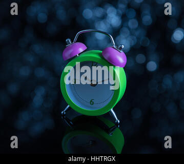 Green alarm clock  on dark background with blue defocused lights Stock Photo
