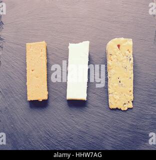 Three cheese selection served on black slate Stock Photo