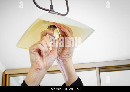 Man installing or changing a bulb, fixing it to the socket at home Stock Photo