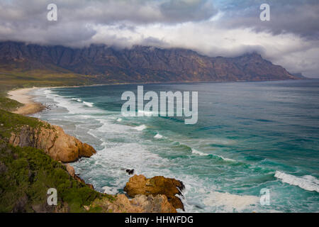False Bay beach along Clarence Drive with view of Kogelberg mountains covered in clouds Stock Photo