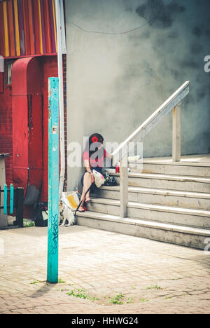beautiful woman sitting on city stairs against gray cement wall Stock Photo