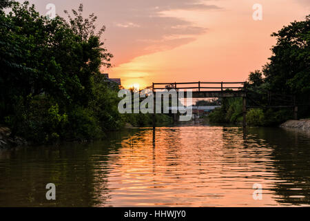 Landscape small canals, water is used as a thoroughfare rural and old wooden bridge for crossing the water during sunset in Phra Nakhon Si Ayutthaya Stock Photo