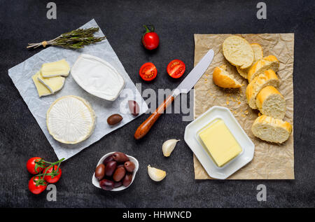 Camembert Soft Cheese, Brie and French sliced Bread with food on Dark Table Stock Photo