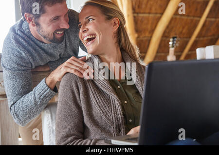 Happy couple laughing and using laptop Stock Photo