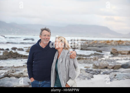 Smiling senior couple walking on winter beach Stock Photo