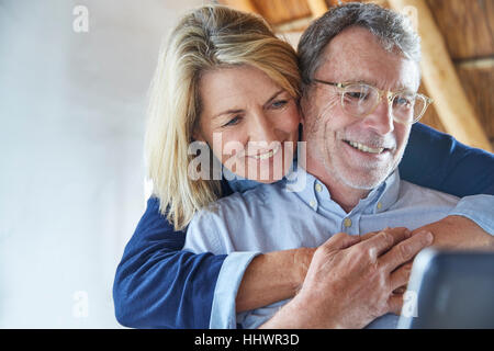 Affectionate couple hugging and using laptop Stock Photo