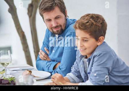 Father and son eating lunch at patio table Stock Photo
