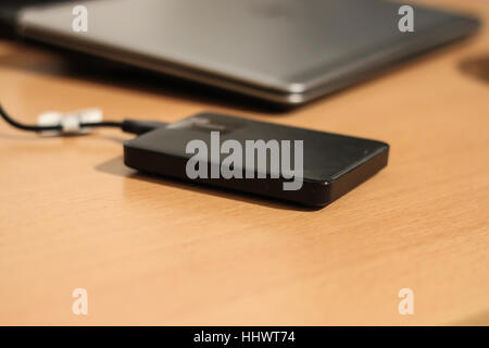 Sleek stylish external HDD connected to silver computer. Stock Photo