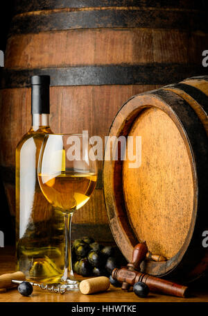 Wine bootle and glass, cheese and grapes in still life on wooden barrel background Stock Photo