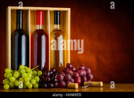 Three bottles of wine with grapes in still life and with copy-space. Red, white and rose Wine Stock Photo