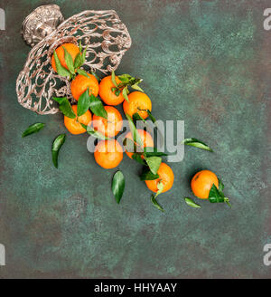 Orange mandarine with green leaves in a vase on dark background. Tangerine fruits Stock Photo