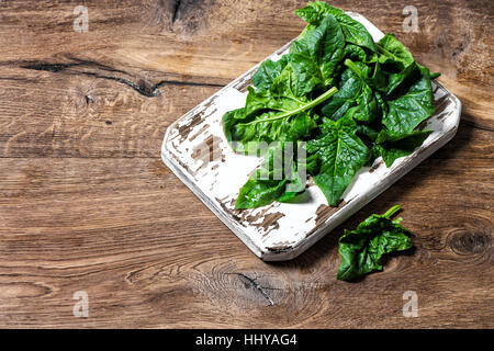 Fresh green spinach leaves on rustic kitchen board. Healthy organic food concept Stock Photo