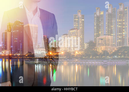 Business leadership concept shown by businessman in suit with urban city background in double exposure. Stock Photo