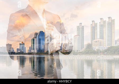 Business leadership concept shown by double exposure of businessman in suit with urban city background. Stock Photo