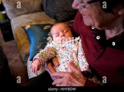 Elderly woman in her eighties cradling a young baby girl in her arms Stock Photo
