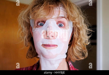 Mature middle aged woman wearing a beauty face mask pack to help ageing skin Stock Photo