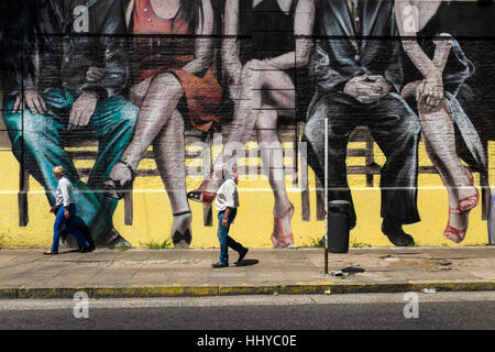 Walking past a city mural depicting sitting couples, Buenos Aires Stock Photo